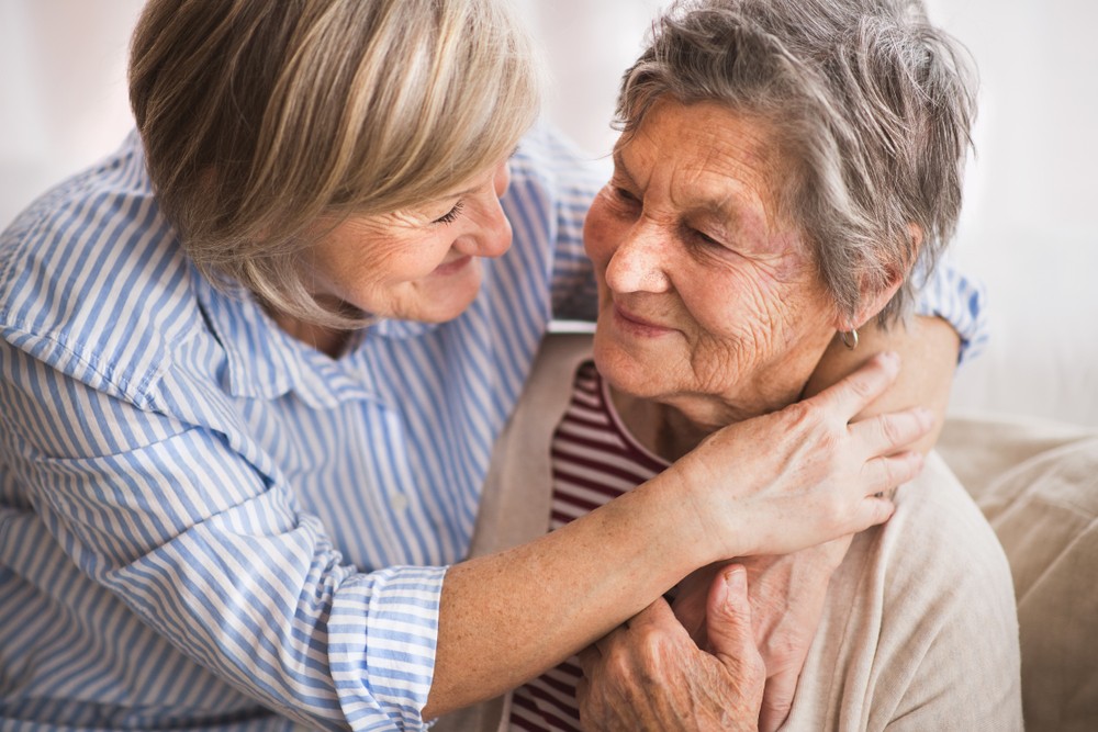 Senior woman embracing parent with dementia