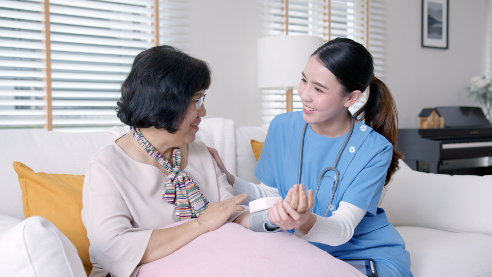 A health care professional checks on a senior woman in short term rehabilitation