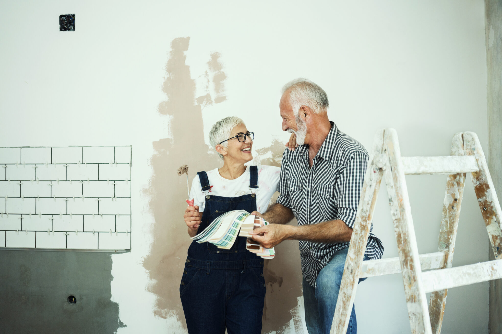 A couple are remodeling their home and adding tile and paint to a wall and take a break together
