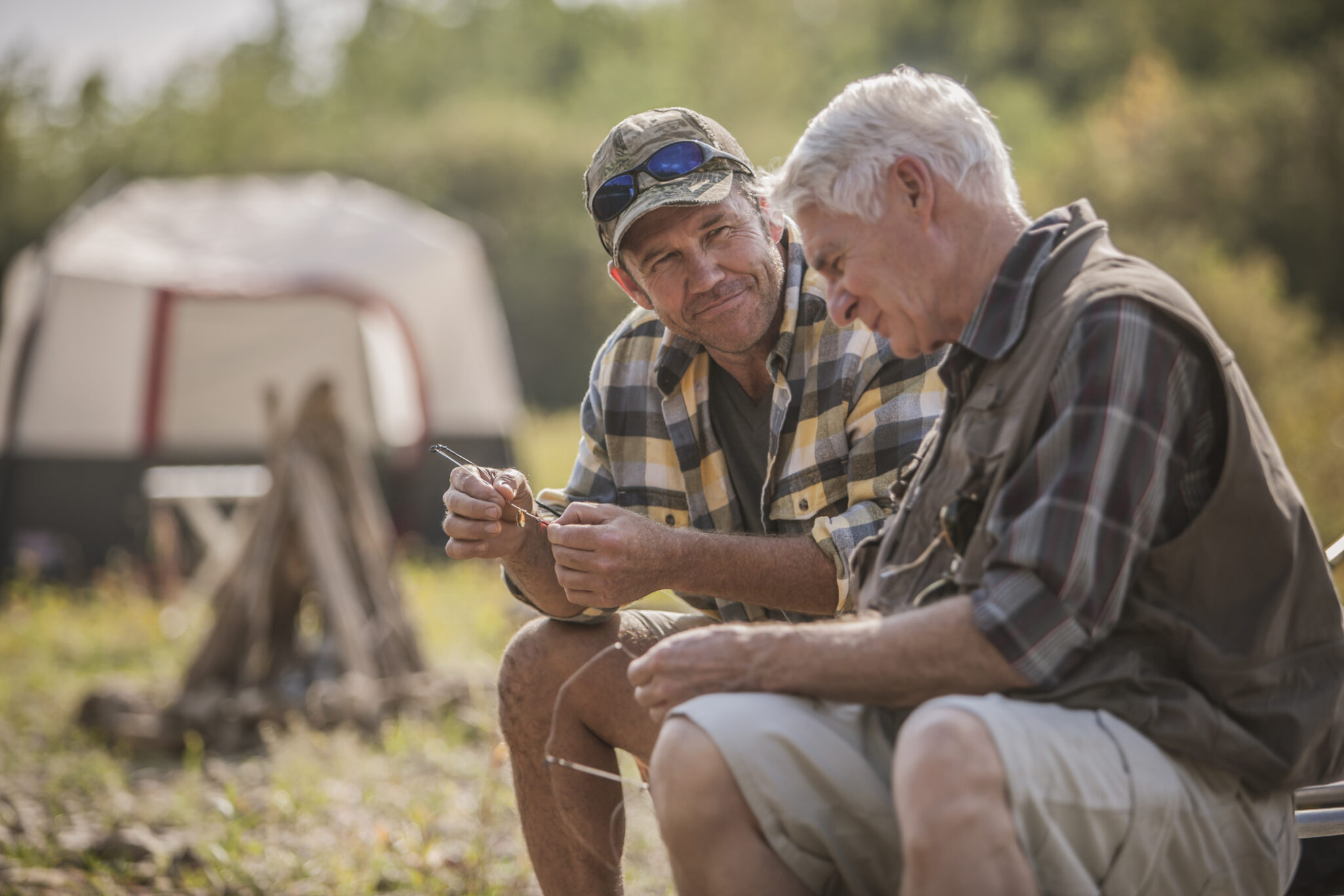 Two older men setting up fishing lures while at a campsite