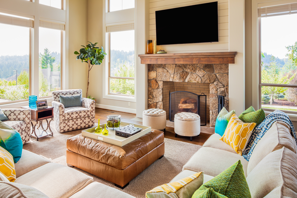 A living room with tall windows, a fire place, and couches and chairs staged to sell a home